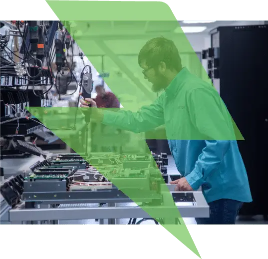 A man in a blue shirt works on electronic equipment in a lab, overlaid with a green geometric design inspired by modern manufacturing website design.