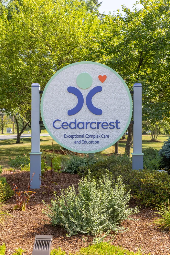 Round Cedarcrest sign in a garden reads Exceptional Complex Care and Education with a heart logo, reflecting the organization&rsquo;s thoughtful brand strategy.