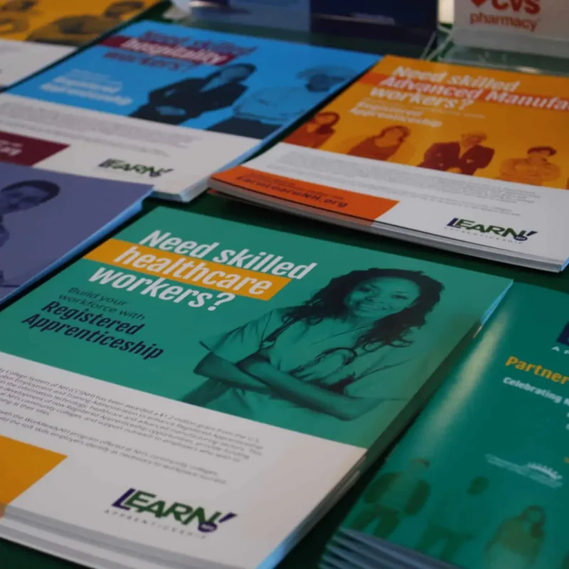 Brochures on a table, one features a smiling healthcare worker and reads Need skilled healthcare workers?&mdash;a smart marketing approach to attract attention.